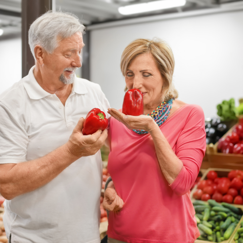 man and woman smelling fresh vegetables